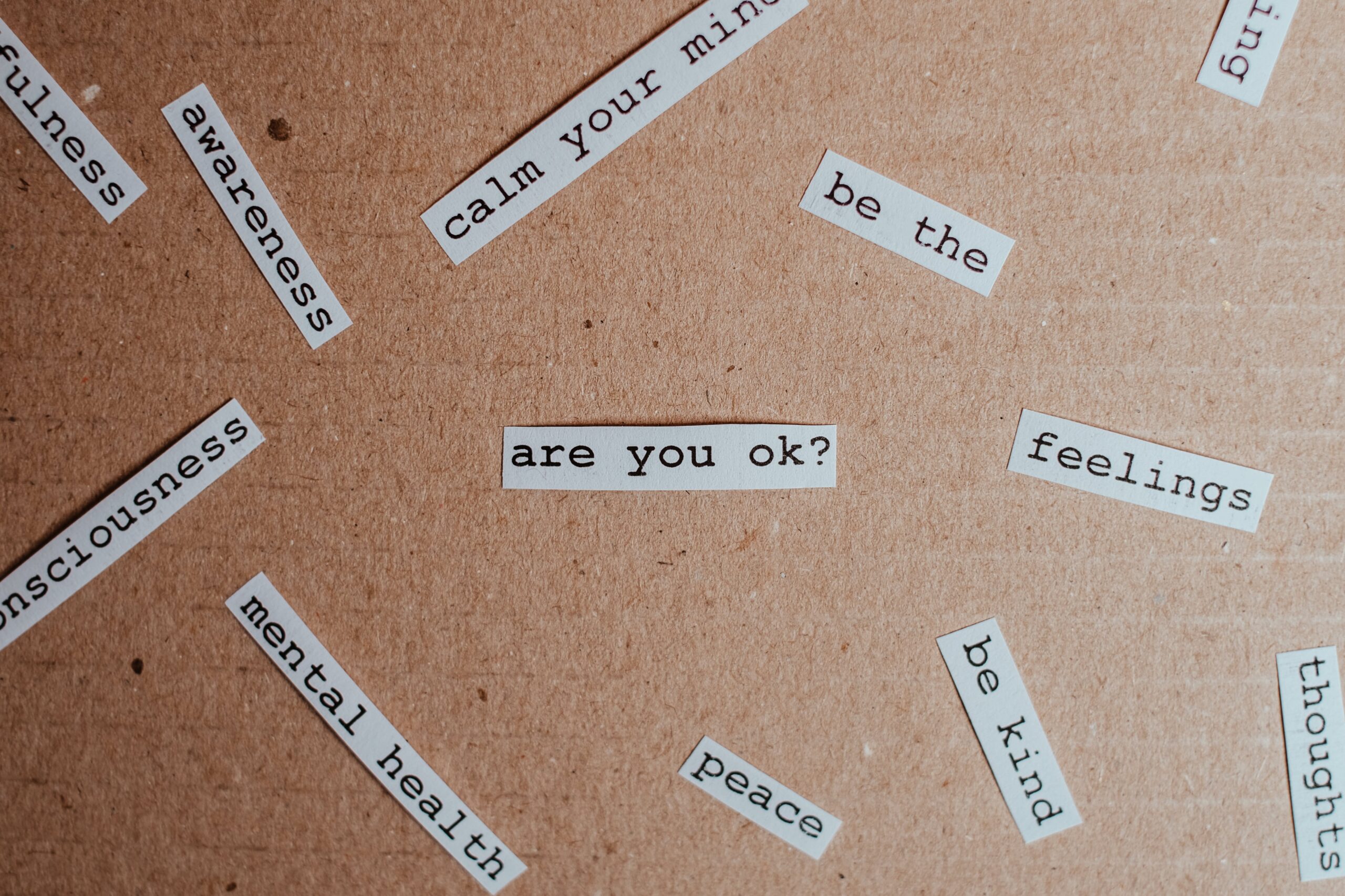collection of cut-out words related to wellbeing and mental health scattered across a board