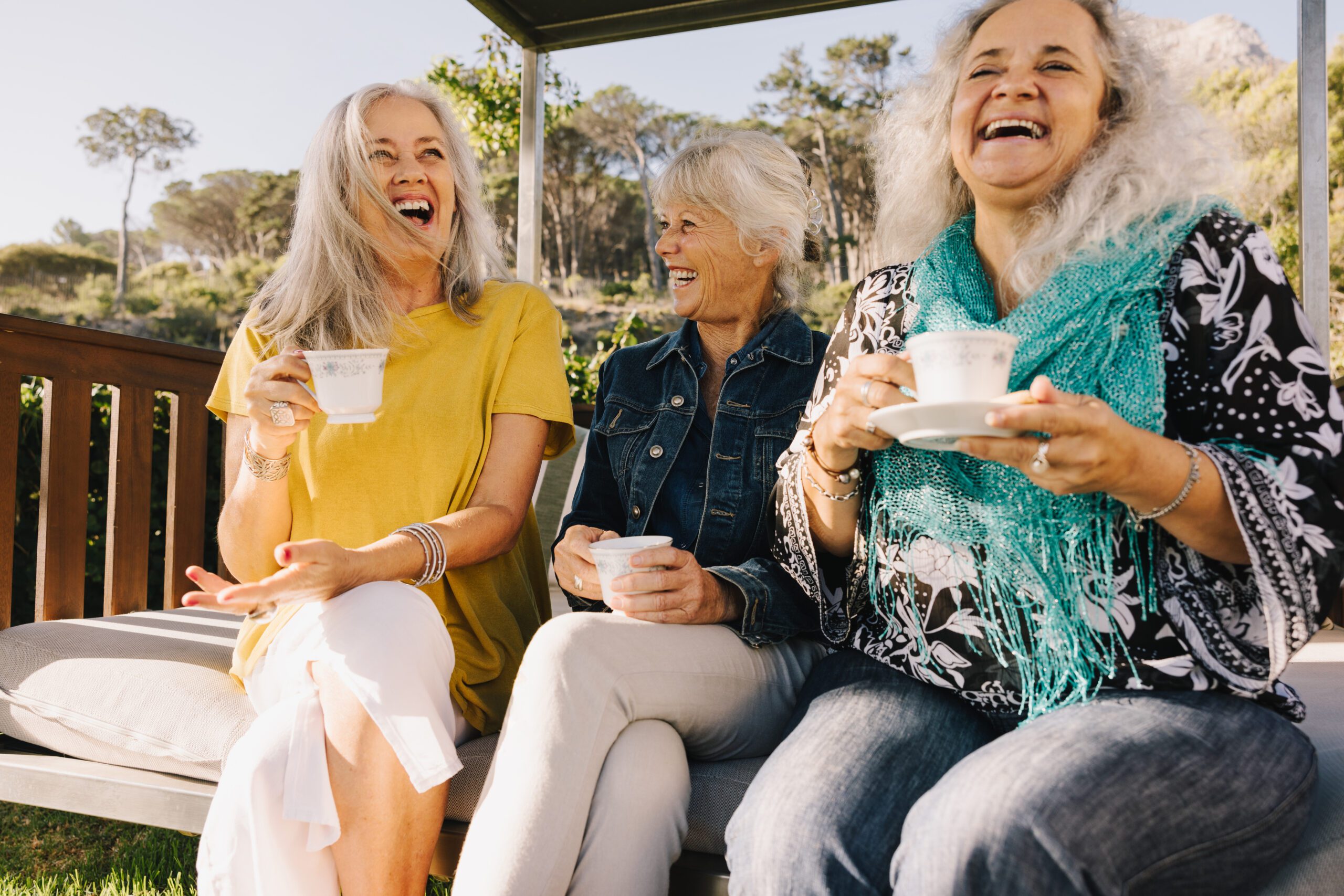 adult female friends laughing happily while having tea